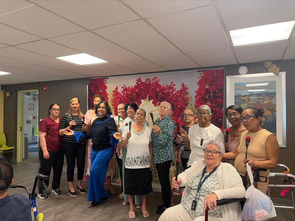 Senior residents and organizers celebrate together, holding roses, at a Senior Music & Lunch event.