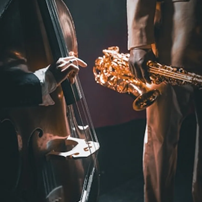 Close-up of an upright bass and saxophones in warm light.